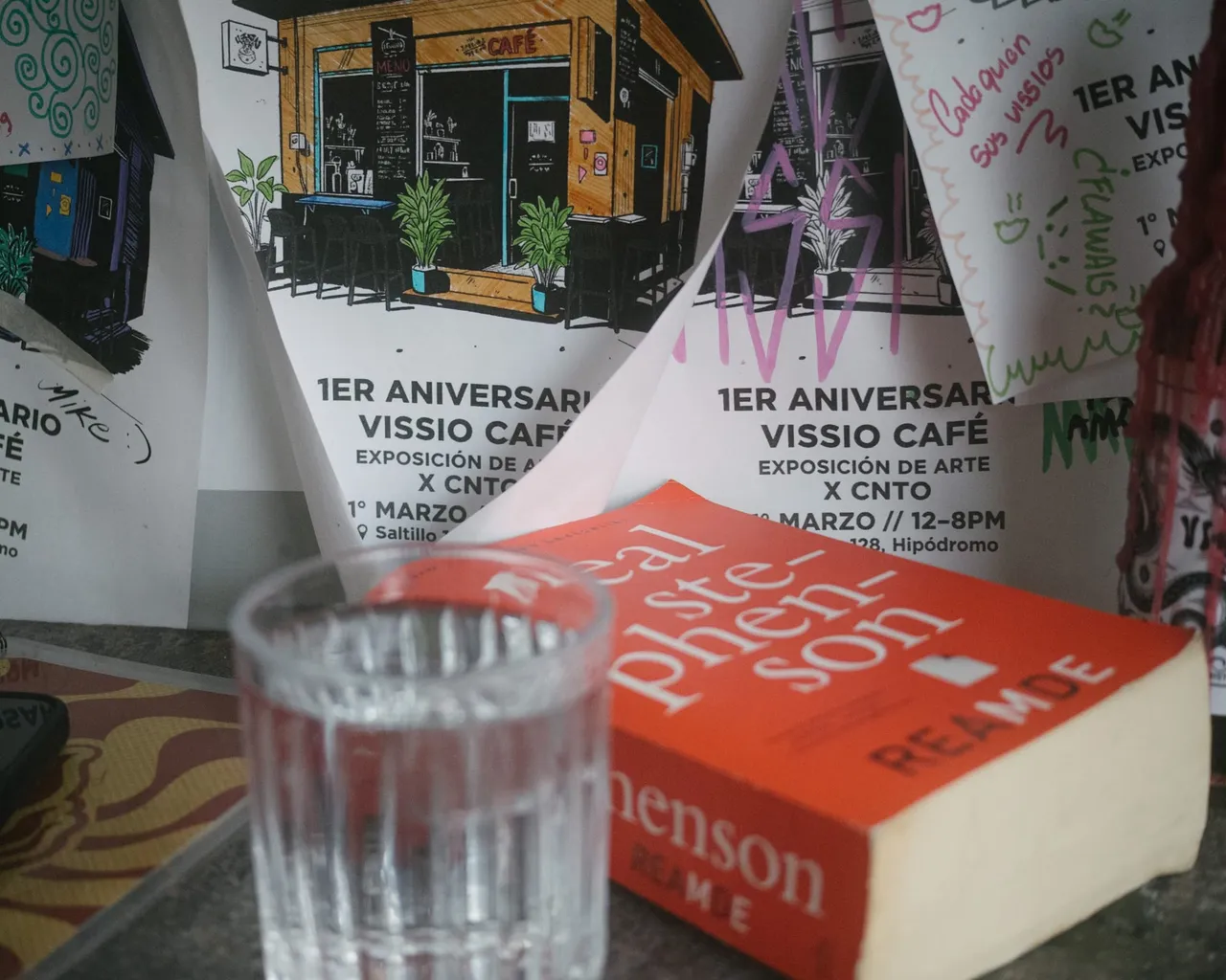 A book, a glass of water and flyers for Vissio's anniversary.